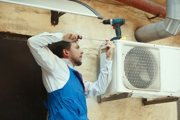 hombre instalando el condensador de un aire acondicionado split