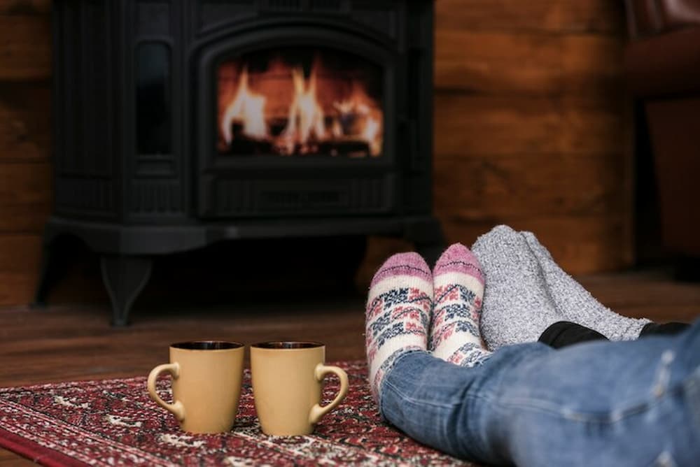 pareja calentando sus pies en chimenea